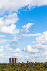 夏季城市建筑和绿林上空有白云的蓝天空图片