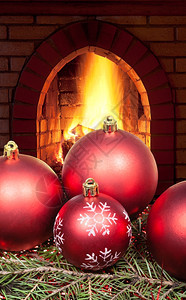 红圣诞球在绿生树上家里壁炉着火图片