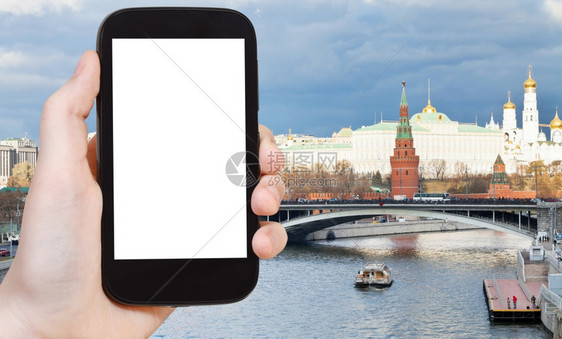 旅行概念手持智能机切断屏幕和桥梁莫斯科克里姆林宫背景图片