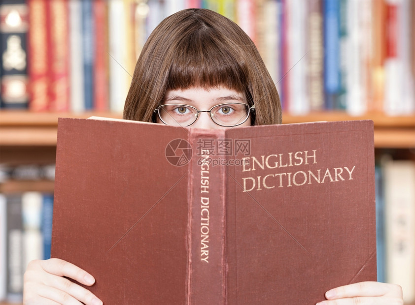 有眼镜的女孩看英语词典书本和背景架图片