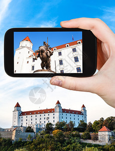 旅行概念在布拉迪斯发赫德城堡用智能手机拍摄斯瓦托普卢克一世国王雕像的旅游快照图片