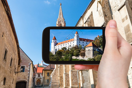 旅行概念利用智能手机从旧城法斯卡街用智能手机拍摄布拉迪斯发赫德城堡的旅游快照图片