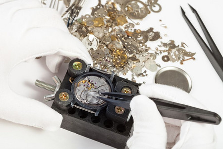 制表手由白色背景零件的tweezers修理机械手表高清图片