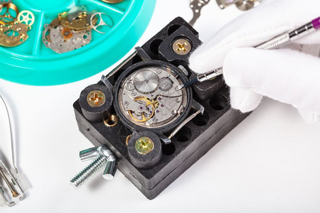 钟表制工场修补白色桌子上的旧机械手表图片
