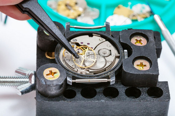 手表制作车间修理持着旧手表的关闭tweezer图片