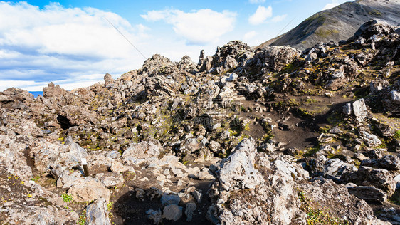 前往冰岛高地区Fjellabak自然保护区Landmannalaugar地区的Laughahraun熔岩场火山斜坡上的岩石图片