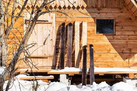宽大的猎人在木屋前滑雪在阳光明媚的冬日里在俄罗斯斯摩棱斯克地区的俄罗斯村庄里一个宽大的猎人在木屋前滑雪图片