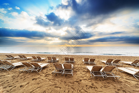 日出时沙滩上的甲板椅子图片