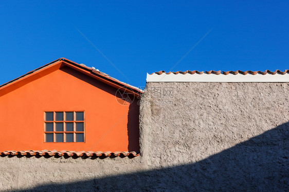 天空背景上的橙色房子窗口和墙图片
