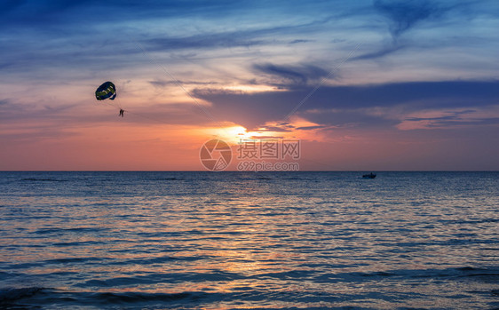 在日落的天空中乘降伞的轮椅图片