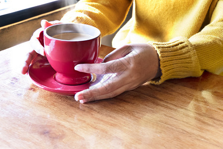 手握着一杯热咖啡的女士手放在木制桌上的手握咖啡杯的亚洲女图片