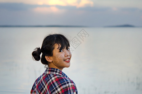 一位美丽的年轻亚洲女孩肖像她对着镜头微笑光亮的美丽年轻亚洲女孩图片