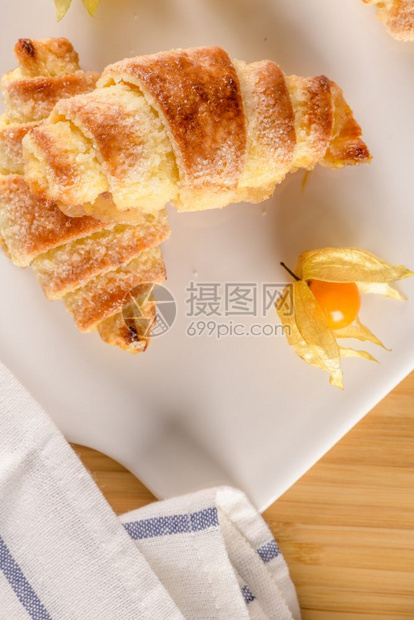小羊角面包白色陶瓷盘里有花生水果木桌顶上有自制蛋糕图片
