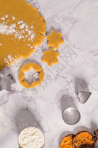 大理石表面的圣诞饼干和切刀的原始面粉图片