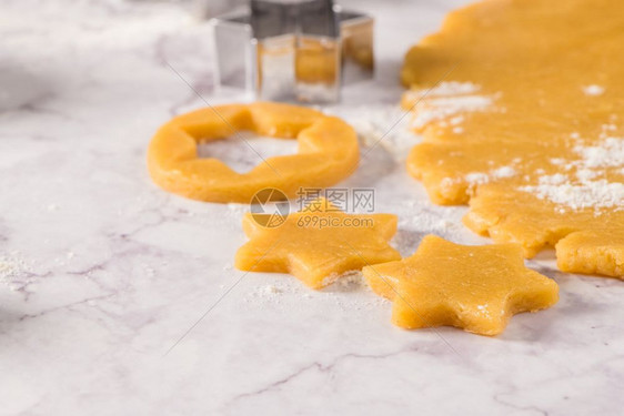 大理石表面的圣诞饼干和切刀的原始面粉图片