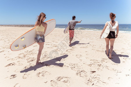 男孩和女少年冲浪者与板走在沙滩上图片