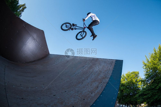 Bmx特技表演在滑板场的迷你坡道顶部图片