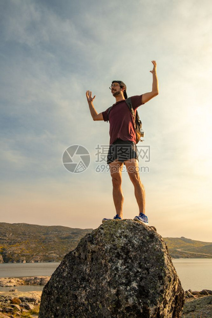 带着背包在山坡顶庆祝成功旅行的人在岩石山上积极享受健康的生活方式图片