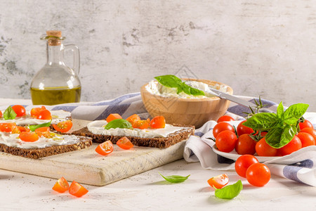 奶油酪橄榄和巴西尔酱樱桃红柿木板上新鲜的巴西尔叶图片