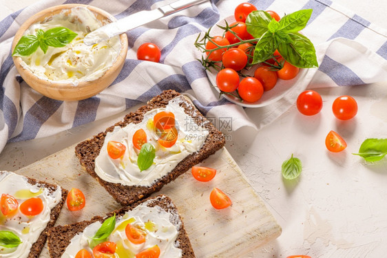 奶油酪橄榄和巴西尔酱樱桃红柿木板上新鲜的巴西尔叶图片