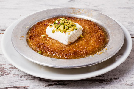 美味的土耳其传统甜点库尼夫配有活塞和奶油图片