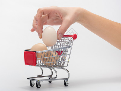 一只手把鸡蛋放进小型购物车图片