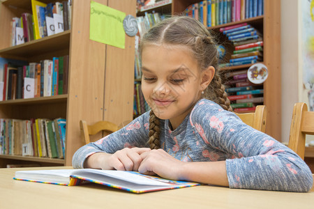 一个微笑的女孩在阅览室看书图片