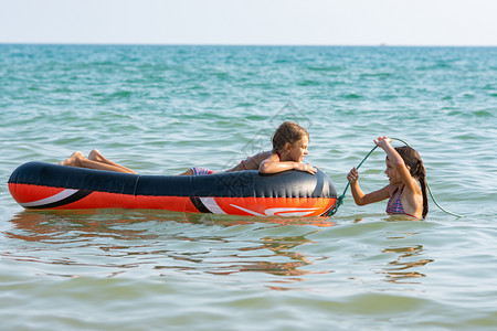 两个女孩在海中游泳用一条充气船在海中游泳图片