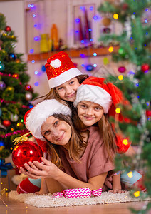 妈和两个女儿躺在新年内地一棵圣诞树的板上图片