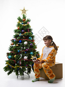 少女坐在圣诞树的盒子上检查圣诞树图片