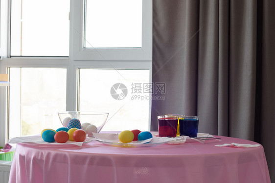 房间窗边内装有彩色鸡蛋和染色剂的桌子图片