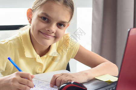 在电脑屏幕前做功课的快乐女孩特写肖像图片