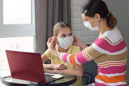 妈坐在家里的电脑前给一个女孩戴上医疗面罩图片