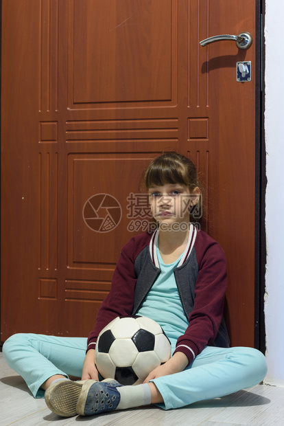 一个带着球的女孩坐在门前悲伤地坐着图片