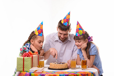 爸和两个女儿用刀子切了一个生日蛋糕图片