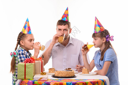 爸和两个女儿在节庆桌边喝果汁图片