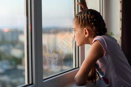 在家被隔离的无聊女孩看着窗外的图片
