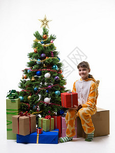 快乐的小女孩坐在圣诞树旁边拿着新年礼物图片
