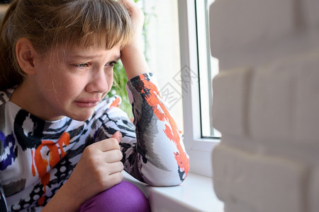 坐在窗边哭着的伤心女孩图片