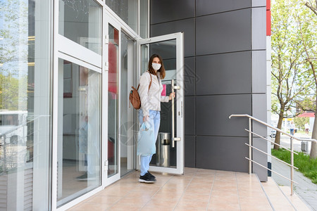 女孩穿着医疗面具和购物时戴着医疗面具走出商店图片