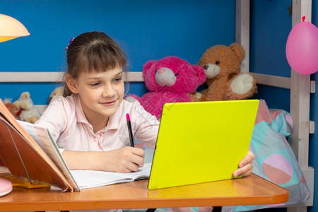 儿童房间里的女孩坐在一张桌子上网学习图片