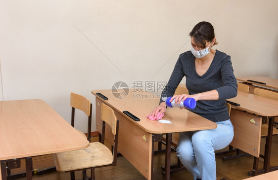 在隔离期间女孩在学校的桌子上泼洒清洁和消毒剂图片