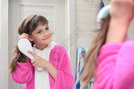 梳长头发的快乐女孩看着镜子图片