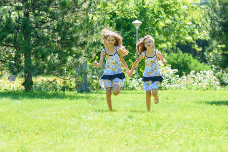两个小妹在公园的绿草坪上跑图片