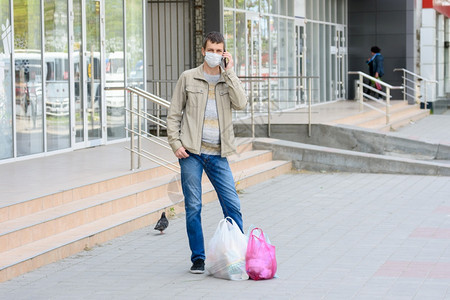 一名身戴医疗面具的人站在街上购物图片