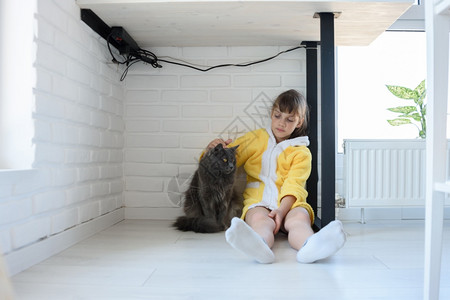 坐在桌子下摸着一只家猫被惩罚的女孩图片