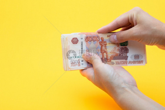 两只手拿着五千个俄罗斯卢布的甲壳类黄色背景图片