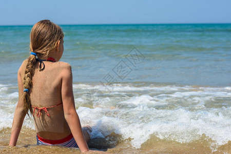 一个女孩坐在沙海滨上看着距离图片