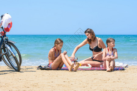 孩子们在温暖的夏日看着妈在海边喝茶杯图片