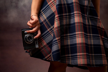 女孩手握着相机拍灰色背景的摄影棚图片